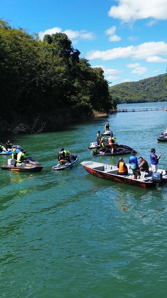 Comboio de jet skis parado em braço do lago cercado de mata